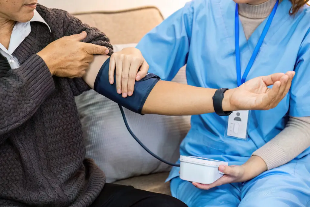 Health care provider take care of elderly by helping to check their blood pressure.