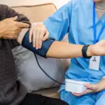 Health care provider take care of elderly by helping to check their blood pressure.
