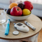 Close up of diabetes supplies and devices on the table. Continuous glucose monitor, insulin pen, blood glucose meter. Image with copy space.