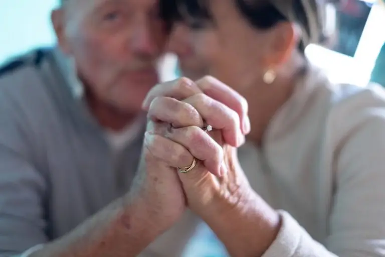 Close up on defocused caucasian couple holding hands. Smiling old couple out of focus. Concept of love, care, support, help, unity. Together they are stronger