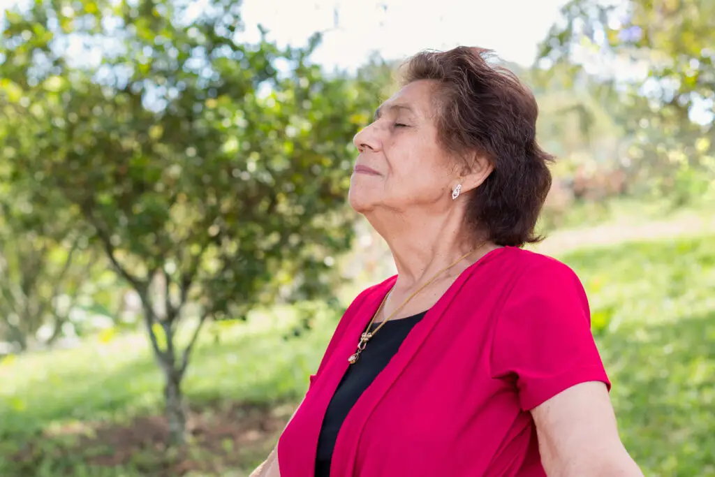 Old woman in her 80s enjoying a fresh and healthy morning breathing exercises outside