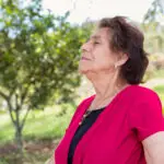 Old woman in her 80s enjoying a fresh and healthy morning breathing exercises outside